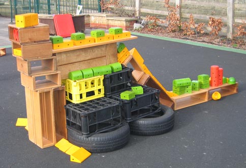 Nursery school children construct a dinosaur in the playground.