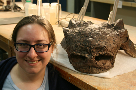 Dr Victoria Arbout next to a Euoplocephalus skull.