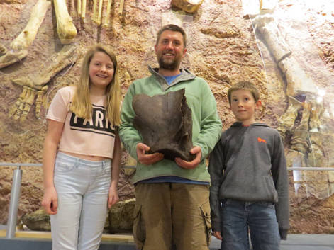Paul and his family show off their fossil find behind an Iguanodon exhibit.