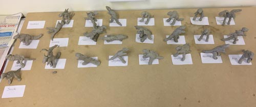 Schoolchildren make clay models of dinosaurs.