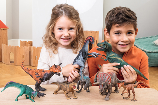 Children playing with Schleich dinosaur and prehistoric animal models.